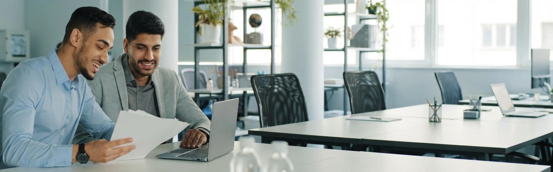 two people reviewing docs and laptop in office